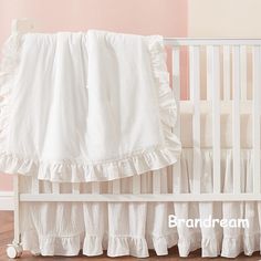 a white crib with ruffled bedding and pink walls