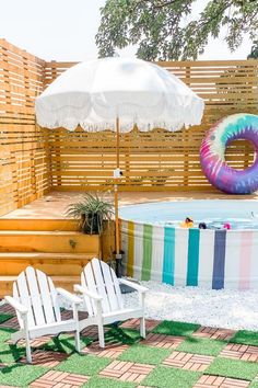 two lawn chairs sitting in front of an above ground pool with a rainbow striped cover