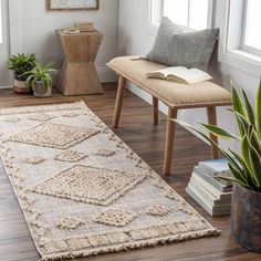 a living room area with a rug, chair and books on the floor in front of a window