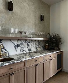 a kitchen with marble counter tops and wooden cabinets, gold faucet handles on the sink