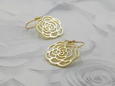 These are pair of beautiful camellia rose earrings. They are made with golden plated over brass flower shaped filigree pendants. The flower is available in two different golden color. The gold color is in a deep gold; and light gold color is in a light gold tone. The earrings measure about 31mm (1.25 inches) from the top of the ear wires to the bottom of the flower. They are perfect for many occasions, gift giving or as a little treat for yourself. Your earrings will presented in a jewelry gift Pierced Brass Flower Earrings For Wedding, Wedding Brass Flower Earrings, Wedding Flower Earrings In Brass, Gold Rose Design Earrings For Anniversary, Brass Flower Earrings For Wedding, Flower Shaped Brass Wedding Earrings, Flower-shaped Brass Wedding Earrings, Yellow Gold Brass Flower Earrings For Wedding, Gold Flower Earrings For Wedding