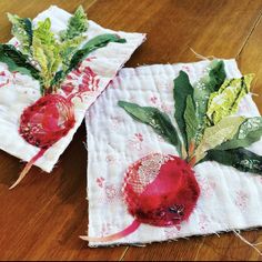 two pieces of cloth with flowers on them sitting on a wooden table next to each other