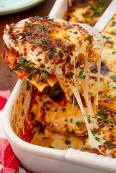 a casserole dish with cheese and vegetables being lifted from the casserole