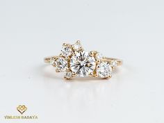 three stone diamond ring on white surface with gold band and center stone surrounded by smaller round diamonds