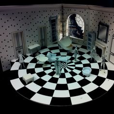 a black and white checkered floor in a doll house with furniture on it's side