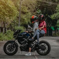 two people sitting on the back of a motorcycle