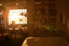 the sun shines through an open window into a bedroom with a bed, desk and bookshelf