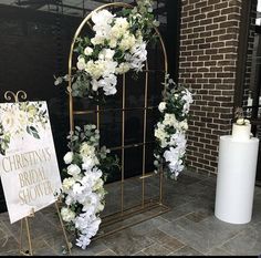 white flowers and greenery on display in front of a brick building