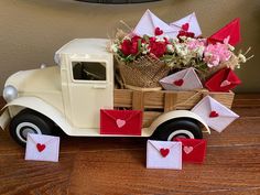 an old fashioned truck with flowers and envelopes in the back, on a wooden table