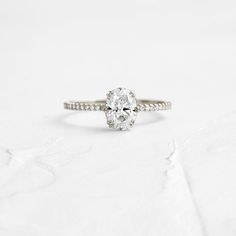 a yellow gold engagement ring with an oval cut diamond in the center on a white background