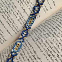 an open book with a blue and yellow beaded bracelet on it's edge