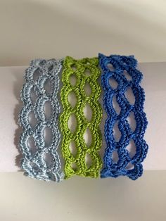 three bracelets are sitting on top of a white napkin with blue and green crochet