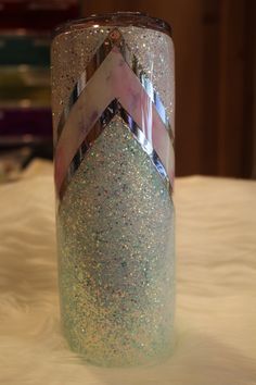 a close up of a cup on a table with glitters and ribbons around it