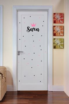 a door with the name sara on it in front of a chair and wall art