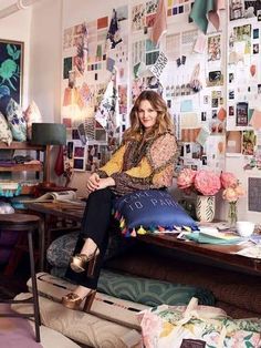 a woman sitting on top of a couch in front of a wall covered with pictures