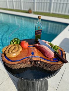 a wooden cutting board sitting next to a swimming pool with food on top of it