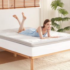 a woman laying on top of a white mattress