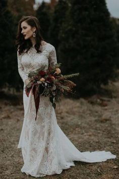 a woman in a white dress holding a bouquet and wearing a long sleeved wedding dress