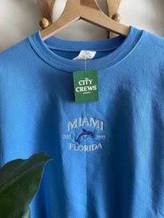 Miami Embroidered Crewneck unisex sizing  fits true to size  50/50 cotton  light weight crewneck, perfect for spring / summer DESIGN OWNED BY CITY CREWS LLC MAY NOT BE REPLICATED OR STOLEN Summer Crewneck, Summer Hoodie, Cute Beachy Sweatshirts, Miami Style, Florida Sweatshirt, Florida Hoodie, Miami Sweatshirt, Summer Hoodies, Miami Graphic Tee