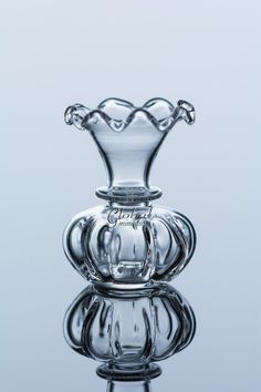 a clear glass vase sitting on top of a reflective surface