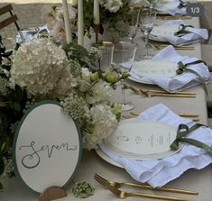 the table is set with white flowers and place cards