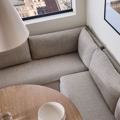 a living room with a couch, table and lamp next to a window overlooking the city