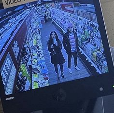 a television screen showing two women walking down the aisle in a grocery store with video on it