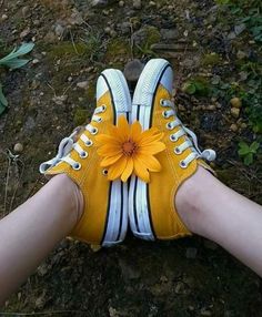 someone wearing yellow tennis shoes with a flower in their shoe