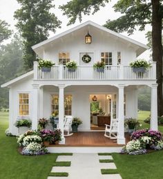 a white house with porches and flowers on the front