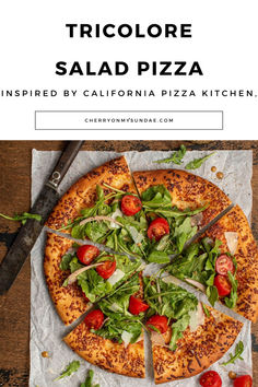 a pizza sitting on top of a cutting board next to a knife and fork with the words, tricolore salad pizza inspired by california pizza kitchen