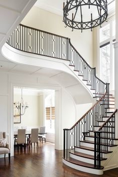 an elegant staircase in the middle of a living room with white walls and wood floors