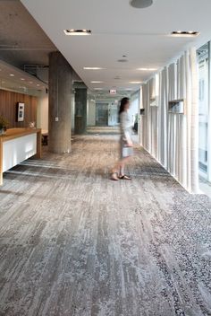 a woman is walking through an office lobby with large carpeted flooring and walls