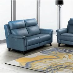 two blue leather sofas sitting on top of a rug