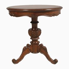 an antique wooden table with carved legs and a round top, on a white background