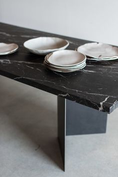 a black marble table topped with white plates