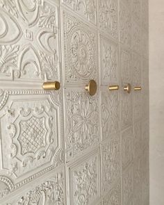 an ornate white wall with gold handles and knobs