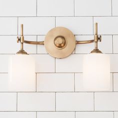 three lights are on the wall in front of a white brick wall and tile floor