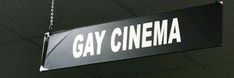 a sign that says gay cinema hanging from a chain in front of a black wall