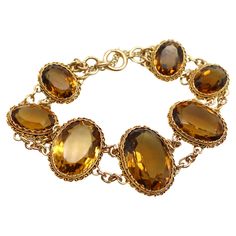 What makes this Victorian 14k gold bracelet so beautiful are the magnificent, well-matched amber hued citrine gemstones that have stunning presence on the wrist. The stones graduate in size with the largest stone as the centerpiece, measuring 22 x 16 x 10.5 mm. The presentation is rich, warm facets of citrines that dominate the overall look of the bracelet. The stones are bezel set into gold that is crimped around the edges, framed by Etruscan Revival wirework. The gemstones are held together by Double Chain Bracelet, Golden Amber, Amber Stone, Double Chain, Citrine Gemstone, Gemstone Bracelet, So Beautiful, Spring Rings, Link Bracelets