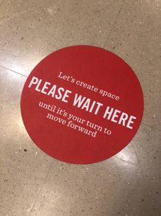 a red sign that says, let's create space please wait here until it's your turn to move forward