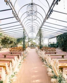 an outdoor wedding venue with lots of wooden benches and tables covered in white pamodia