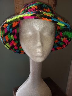 a white mannequin head wearing a multicolored hat