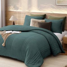 a bed with green comforter and pillows in a bedroom