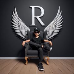 a man sitting in a chair with wings on the wall behind him, wearing sunglasses and a baseball cap