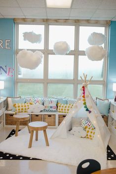 a child's playroom with a teepee tent in the corner and pillows on the floor