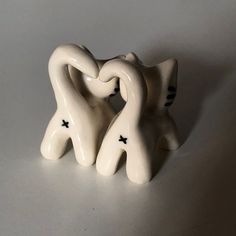 two white ceramic figurines sitting next to each other on a gray table top