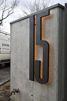 a concrete sign with the letter g on it and a white van in the background