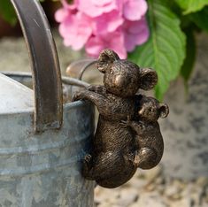 a little teddy bear sitting on its hind legs in a bucket next to some flowers