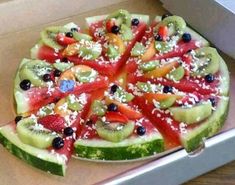 a pizza in a box with lots of different fruits on the top and bottom half