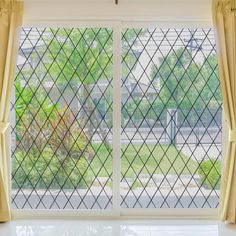 an open window with yellow curtains and green trees in the background